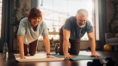 Happy Middle Aged Couple Doing Gymnastics and Yoga Stretching Exercises Together at Home on Bright Morning. Senior Man and Woman Motivate Each Other