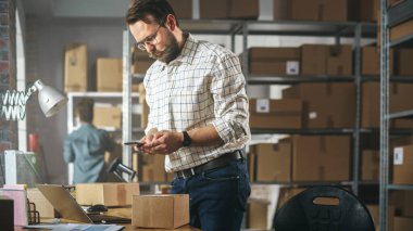 Storeroom Inventory Worker Using Smartphone to Scan a Barcode on Parcel, Preparing a Small Cardboard Box for Postage. Small Business Owner Working on