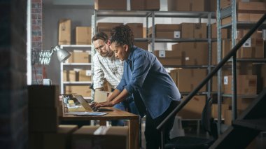 Warehouse Inventory Manager and Worker Using Laptop Computer, Preparing a Small Parcel for Shipping. Small Business Owners Working in Storeroom