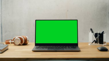 Laptop Computer with Mock Up Green Screen Display Standing on a Desk. Efficiently Minimalistic Design of Modern Office Space That Guarantees Harmony