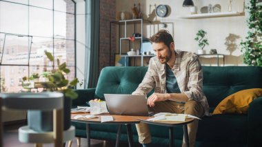 Accounting at Home: Streessed Man Using Laptop Computer, Filling Tax Forms. Businessman Scared of Bankruptcy. Paperwork Problems: Bills, Invoices