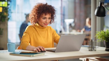 Şirket ofisinde dizüstü bilgisayarda çalışan yaratıcı çok ırklı kadın. Mutlu Heyecanlı Proje Yöneticisi İnternet Taraması, Yazma Görevleri, Geliştirme