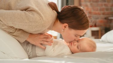 Mutlu Anne Yatakta Uzanıyor, Evde Sevimli Yeni Doğmuş Bebekle Oynuyor. Anne 'nin bir bebekle bağ kurması, Neşeli Çocuğu Yukarıda Tutması. Konsept