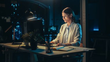 Akşam geç saatlerde ofiste çalışan genç bir muhasebecinin portresi. Pozitif Kadın Masaüstü Bilgisayarı Kullanımı, Görev Ataması Hazırlanıyor ve