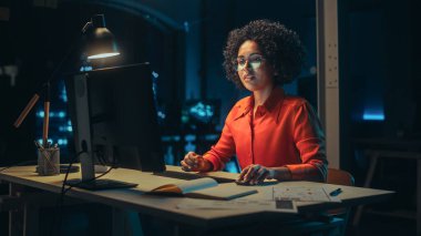 Genç Siyah Kadın Akşamları Yaratıcı Ofiste Masaüstü Bilgisayarı üzerinde çalışıyor. Mutlu Çoklu Etnik Proje Yöneticisi E-posta Yazıyor, Araştırıyor
