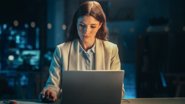 Yetenekli Dijital Pazarlama Uzmanı Akşam Ofisinde Dizüstü bilgisayar üzerinde çalışıyor. Genç İşkadını Yaratıcı Acentede Bilgisayar Kullanıyor, Kontrol Ediyor