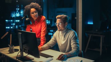 Geceleri Ofiste Masaüstü Bilgisayarı üzerinde çalışan Proje Yöneticisi. Genç Çok Irklı Uzman, İş Geliştirme Hakkında Görüşmek için Masaya Geldi