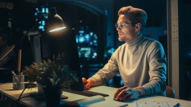 Geceleri Şirket ofisinde Masaüstü Bilgisayarı 'nda çalışan yakışıklı adam. Genç Uzman Analiz Raporları. Pazarlama Asistanı Bir Tüketici Geliştiriyor