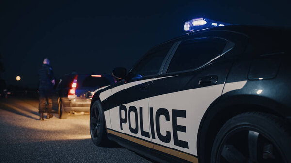 Портрет кавказского полицейского средних лет, приближающегося к остановке автомобиля с осторожностью. Пьяного водителя остановил офицер, чтобы проверить его документы.