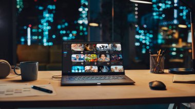 Ekranda Görüntü Yayını Platformu ile Masada Duran Dizüstü Bilgisayar. Bilgisayarlı masa, kahve kupası, kulaklık ve yaratıcı not defteri.