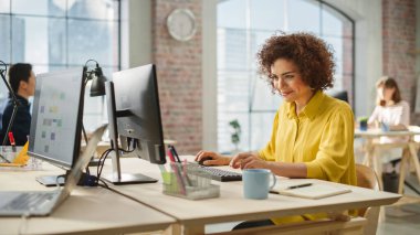 Çift ırklı Kadın, bir iş projesini başarıyla bitirdiğinde mutlu bir şekilde gülümser. Gündüzleri bilgisayarlar üzerinde çalışan çok ırklı Yaratıcı Meslektaşlar Grubu