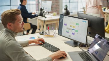 Ofisteki Odaklanmış Genç Beyaz Adam 'ın Portresi Bilgisayar Takvimi üzerinde çalışıyor. Erkek Takım Lideri Verileri Denetliyor ve Bir Zamanlama Hazırlıyor.