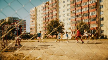 Yazın güneşli bir günde arka bahçelerinde futbol oynayan çok ırklı çocuklar. Neşeli oğlanlar ve kızlar Futboldan Hoşlanıyor