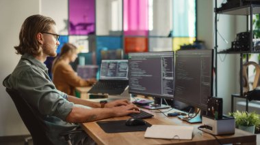 Profesyonel Erkek Geliştirici Masaüstü Bilgisayarında İki Ekran ve Yaratıcı Ofiste Bir Dizüstü Bilgisayarla Kod Yazıyor. Kafkas Adam Yapay Programlama