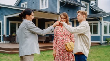 Genç Ev Sahiplerini Yeni Ev Sahipleriyle Tebrik Etme Emlakçınız kutlu olsun. Neşeli çift iş kadınıyla tokalaşıyor ve...
