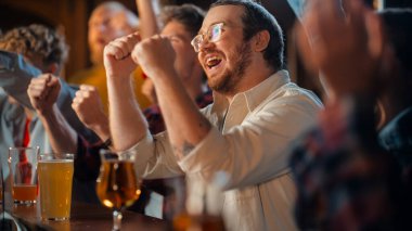 Futbol maçı sırasında spor barında galibiyeti kutlayan mutlu bir gencin portresi. Tezgahta otururken televizyona bakmak...
