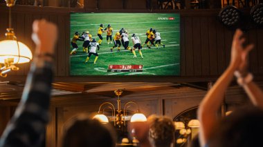 Group of American Football Fans Watching a Live Match Broadcast in a Sports Pub on TV. People Cheering, Supporting Their Team. Crowd Goes Ecstatic clipart