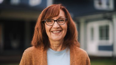 Kızıl saçlı, mutlu bir yaşlı kadının portresi ve bir banliyö evinin önünde duran kahverengi bir Cardigan. Yaşlı Yetişkin