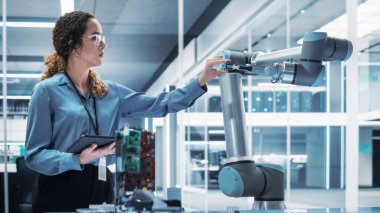 Tablet Bilgisayar kullanan çok ırklı genç bir kadın mühendisin portresi. Robotik Kol Makinesi ile etkileşime girmek, El 'den bir mikroçip almak