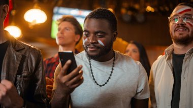 Smartphone Tutan Heyecanlı Genç Bir Siyah Adam 'ın Portresi, En sevdiği futbol takımına Spor Bahsi Hakkında Endişeli. Canlı Başarılı Duygular Ne zaman