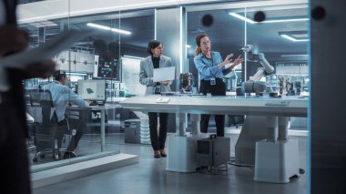 Yüksek Teknoloji Tesisi 'nde çalışan iki kadın. Robot Mühendis ve Makine İşlemcisi Bir Robot Kolu Projesinde İşbirliği yapar, Bir Dizüstü bilgisayar kullanarak