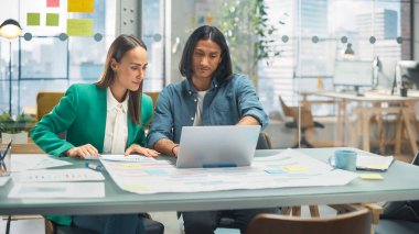 Modern Gündelik Ofis 'te İki Yaratıcı Meslektaşın Dizüstü bilgisayarı Tartışıp İşaret Etmesi. Kafkas Satış Müdürü İspanyol 'la Proje Planını Tartışıyor