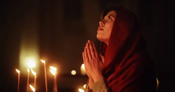 stock image Christian Woman with Head Scarf Getting on her Knees and Praying Near the Candles in a Church. She Seeks Guidance From her Religious Faith and