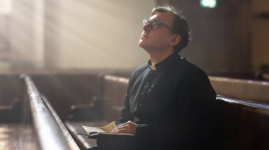 Hıristiyan Kilisesinde: Sessizce dua eden bakanın portresi, kutsal kitaptan, İncil 'den, İsa' nın İncili 'nden, peygamberden okuyor. Rahip.