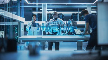 Çok ırklı Endüstriyel Mühendisler Ekibi, prototip Türbin motorlu bir masanın etrafında toplandı. Bilim adamları araştırmak için dizüstü bilgisayar kullanıyor