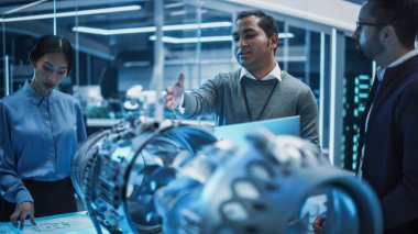 Çok ırklı Endüstriyel Mühendisler Ekibi, prototip Türbin motorlu bir masanın etrafında toplandı. Bilim adamları araştırmak için Tablet Bilgisayar kullanıyor