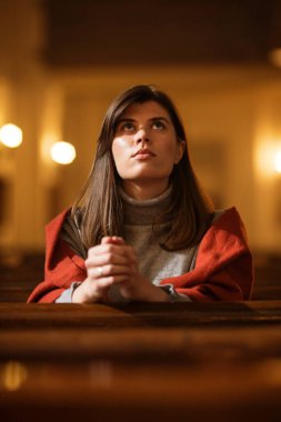 Dindar bir Hristiyan kadın kilisede dindar bir şekilde oturur, dua etmek için ellerini katlar, dini inancı ve ruhaniliğinden rehberlik ister. Ruhu