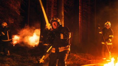 Deneyimli İtfaiyeciler Grubu Ormanın derinliklerindeki Vahşi Diyar Fırça Yangınını söndürüyor. Profesyonel İtfaiyeci Güvenlik Üniforması ve Kask Spreyi