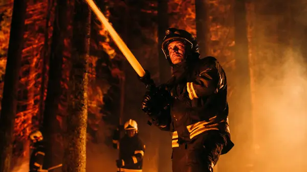 stock image Group of Experienced Firefighters Extinguishing a Wildland Brushfire Deep in the Forest. Professional Fireman Wearing Safety Uniform, Spraying Water