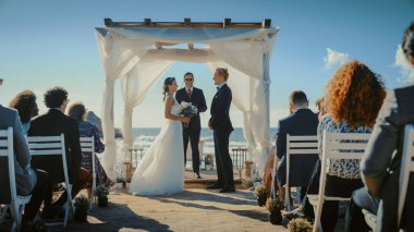 Güzel Gelin ve Damat Ocean Beach 'te bir açık hava düğün seremonisi sırasında. Romantik Çiftler Evlenip Yüzüklerini Değiştirmek İçin Mükemmel Bir Yer