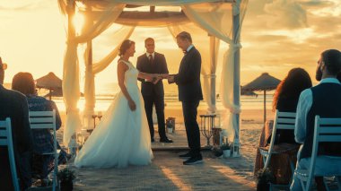 Güzel Gelin ve Damat Sunset 'te bir Ocean Beach' te Açık Hava Düğün Töreni sırasında. Evlenmek, Yüzük Değiştirmek, Öpüşmek İçin Mükemmel Bir Yer