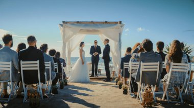 Güzel Gelin ve Damat Okyanus Kıyısındaki Bir Sahilde Açık Hava Düğün Töreni sırasında. Romantik bir çiftin evlenmesi, öpüşmesi ve öpüşmesi için mükemmel bir yer.