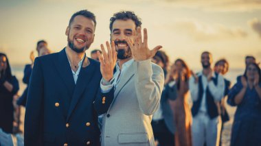 Mutlu, evli, yakışıklı, eşcinsel bir çiftin portresi altın alyanslarını gösteriyor. Takım Elbiseli İki Çekici Gay Adam Gülümseyin ve Poz Verin