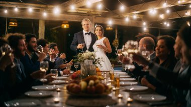 Güzel Gelin ve Damat Akşam Resepsiyonunda Düğünü Kutluyor. Yeni evliler mutlu evliliğe kadeh kaldırmayı teklif ediyor. Yemek masasında ayakta duruyor.