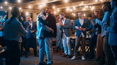 Yakışıklı Mutlu Eşcinsel Çift Çeşitli Çok Irklı Arkadaşlarla Akşam Resepsiyonunda Düğünü Kutluyor. Eşcinsel yeni evliler Dans ediyor ve sarılıyorlar