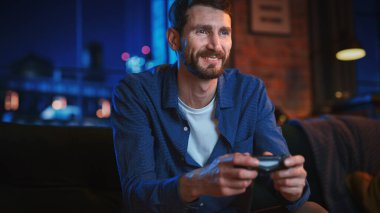 Genç Yakışıklı Adam 'ın Evde Zaman Geçirmesi, Stylish Loft Apartmanında Bir Koltukta Oturması ve Konsolda Video Oyunları Oynaması. Başarılı Erkek