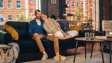 Evlerinde vakit geçiren genç bir çiftin portresi, bir koltukta oturan, apartmandaki heyecanlı TV programını izlerken kız arkadaşını kucaklayan bir adam. Erkek ve