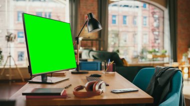 Masaüstü Bilgisayarı 'nda Mock Up Green Screen Ekranı Samimi Oturma Odasında Masanın Üzerinde Duruyor. Arka planda Modern Parlak Ofis Stüdyosunda