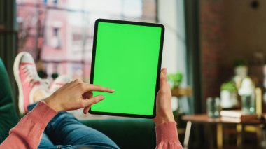 Kadın El Kaydırma Kaydırma Kaynağı Tablet Yeşil Ekran Uygulaması Görünümü ile. Kadın Evdeki Koltukta Rahatlıyor, Video İzliyor ve Sosyal Medya Okuyor