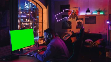 Heyecanlı Siyah Oyuncu Güçlü Kişisel Bilgisayarında Yeşil Ekranla Online Video Oyunu Oynuyor. Oda ve bilgisayar renkli Neon Led Lights 'a sahip