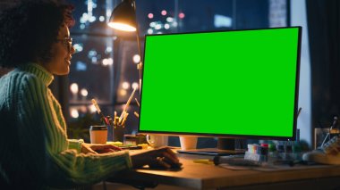 Masasında oturan yaratıcı siyahi kadın, Yeşil Ekran Kromakey ile Masaüstü Bilgisayarını kullanıyor. Fare Kullanan Kadın Uzman, Araya Kaydırıyor