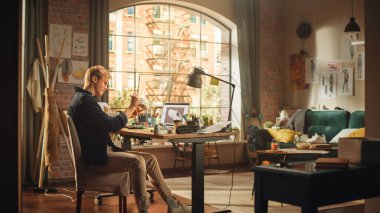 Yakışıklı Genç Erkek Tasarımcı Oturma Odasında Yeni Moda Spor Ayakkabılar Yapıyor. Sanatçı, Kendi Tasarımı ve Kullanımı ile Gümrük Ayakkabıları Ekliyor