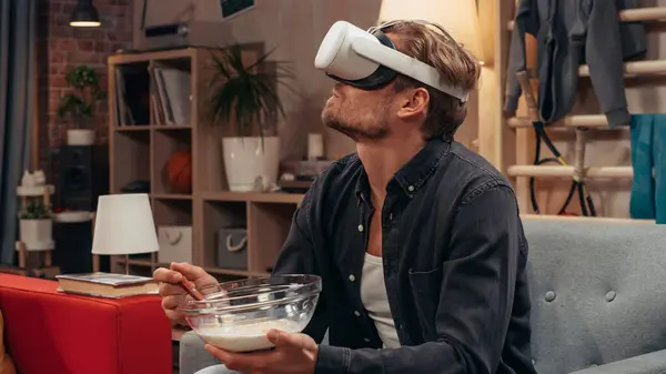 stock image Television Sitcom Concept: Guy Using Virtual Reality Headset Eating Breakfast in Living Room. Funny Sketch About Internet Addiction. Comedy Series