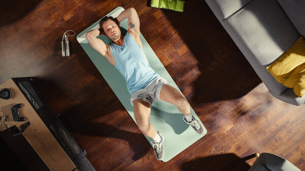 Top View Sport Concept: Gorgeous Male Doing ABS Crunches Lying on an Exericise Mat at at Home. Мускулистый, здоровый, очень красивый атлетичный человек действительно тренируется