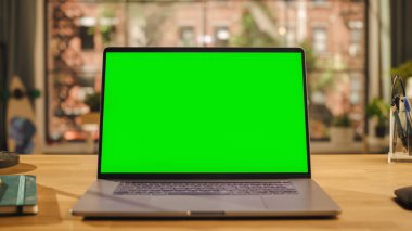 Oturma odasında ahşap bir masada duran Mock Up Green Screen ile dizüstü bilgisayar görüntüsü. Ev veya Yaratıcı Çatı katında Krom Anahtar İzleyiciName