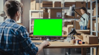 Yeşil Ekran Kromakey Mock Up ile Masaüstü Bilgisayarı Kullanan Genç Adam. Dağıtım Müdürü ve Dağıtım Deposunda Çalışan